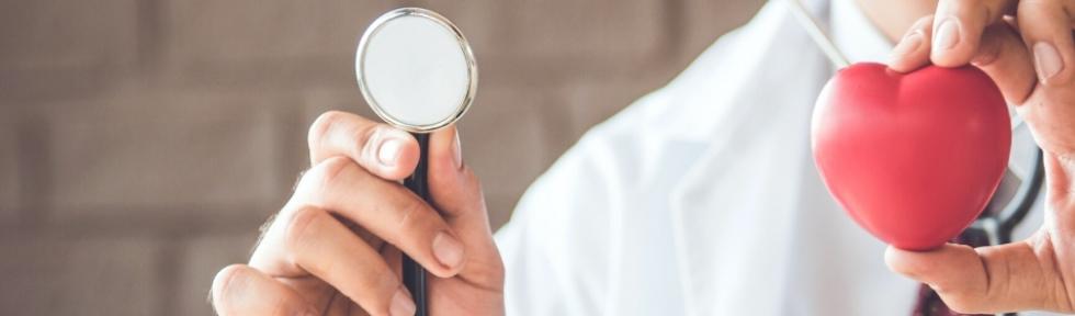 Ręce doktora trzymające stetoskop oraz figurkę w kształcie serca